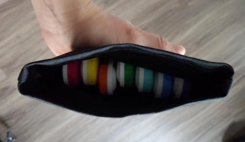 little black satchel, open to show rainbow colored contact lens containers lined up inside it