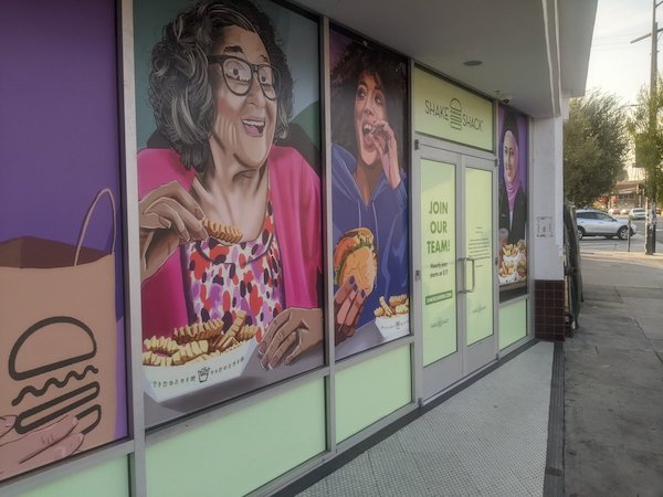 a painted mural on a Shake Shack, with several people shown eating fast food